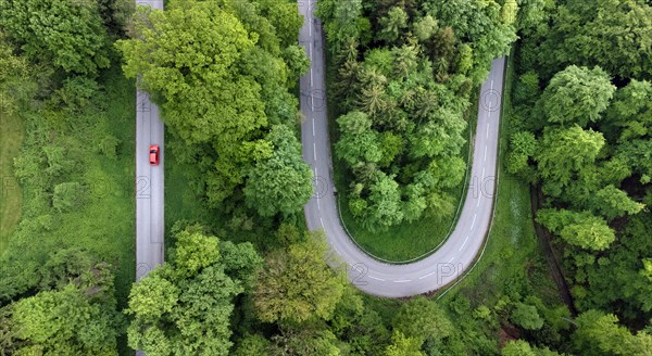 Red car driving on serpentine road through green landscape, drone shot, Upper Bavaria, Bavaria, Germany, Europe