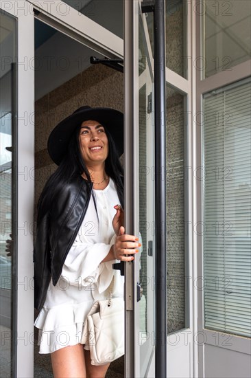 Vertical image of a woman in a black hat coming out of her apartment