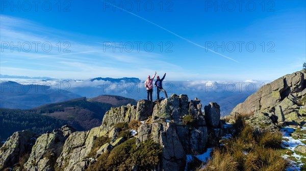 Two men reaching the top of the mountain while trekking