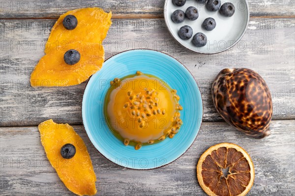 Mango and passion fruit jelly with blueberry on gray wooden background. top view, flat lay, close up