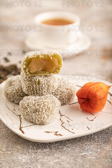 Japanese rice sweet buns mochi filled with pandan jam and cup of green tea on brown concrete background. side view, close up, selective focus