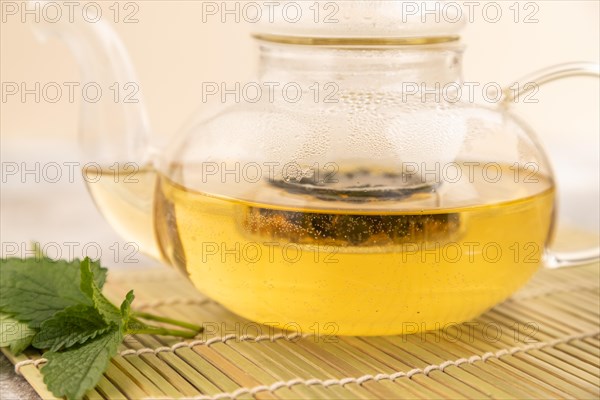 Green oolong tea with herbs in glass on brown concrete background. Healthy drink concept. Side view, close up, selective focus