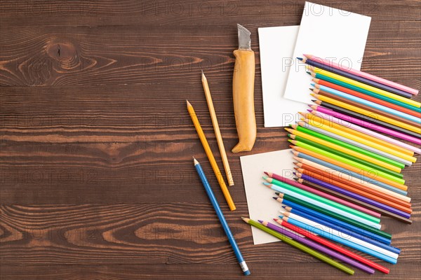 Set of watercolor pencils on brown wooden background. Top view, flat lay, copy space