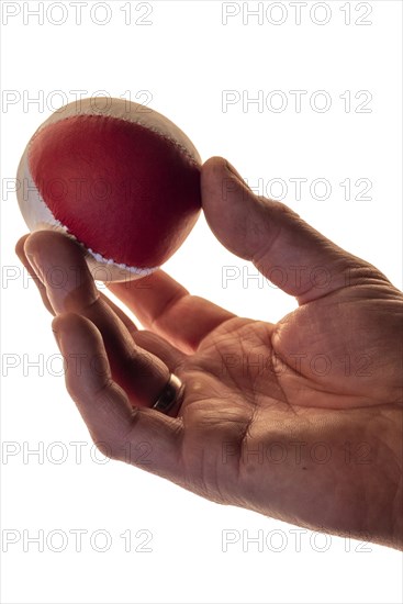 Hand with a juggling ball in front of a white background, studio shot, Germany, Europe