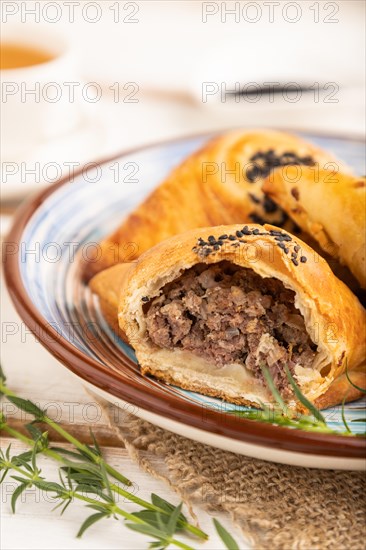 Homemade asian pastry samosa, cup of green tea on white wooden background and linen textile. side view, selective focus