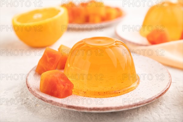 Papaya and orange jelly on gray concrete background and orange linen textile. side view, flat lay, close up, selective focus