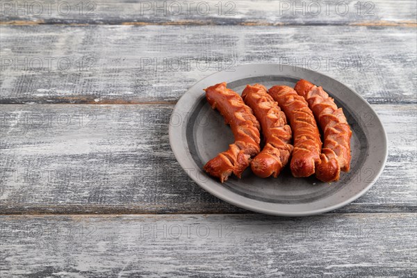 Fried sausage on a gray plate on a gray wooden background. Top view, close up, copy space