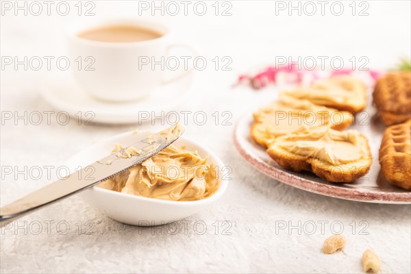 Homemade waffle with peanut butter and cup of coffee on a gray concrete background. side view, close up, selective focus