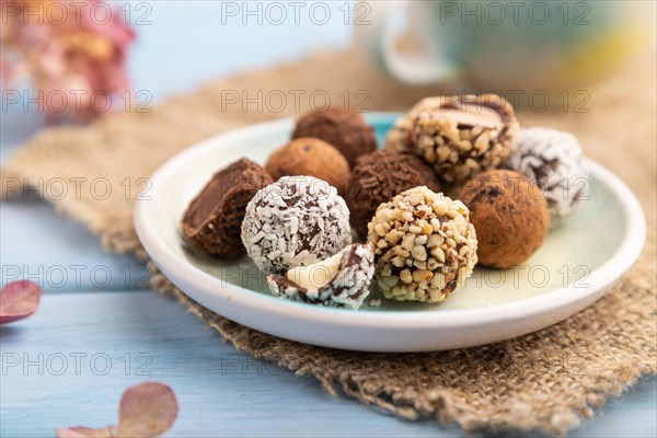 Chocolate truffle candies with cup of coffee on a blue wooden background and linen textile. side view, close up, selective focus