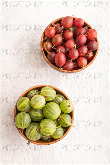 Fresh red and green gooseberry in clay bowl on gray concrete background. top view, flat lay, close up