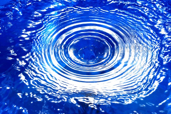 A water vortex in blue water, with concentric circles