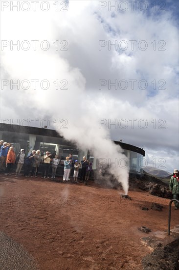 Tourists watch steam rise from geyser spout, Parque Nacional de Timanfaya, national park, Lanzarote, Canary Islands