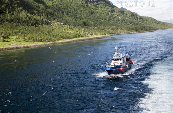 Small tourist boat in mountainous fiord landscape, Raftsundet strait, Nordland, northern Norway