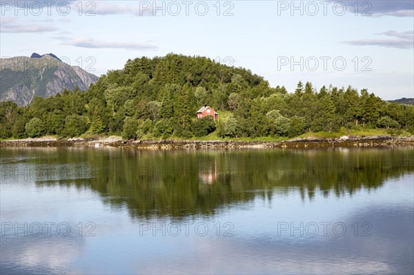 Isolated coastal house on small wooded island near Ornes, Nordland, Norway, Europe