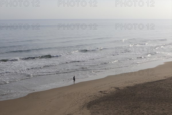 Woman silhouette walking alone along beach shoreline, Bellreguard, near Gandia, Valencia province, Spain, Europe