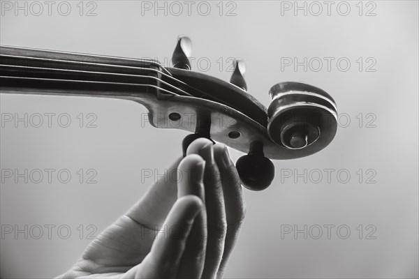 Child's hand tuning viola, black and white photo, studio shot, white background, Germany, Europe