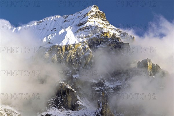 Afternoon mist and clouds gather around the dramatic crags and summit of an un-named peak in the Kangchenjunga region of east Nepal