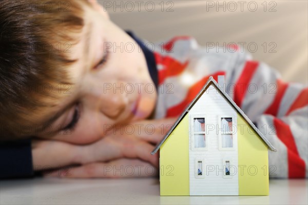 Boy looks longingly at a model house