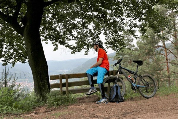 Mountain biker taking a break on a bench in the Palatinate Forest near the Weinbiet above Neustadt an der Weinstrasse