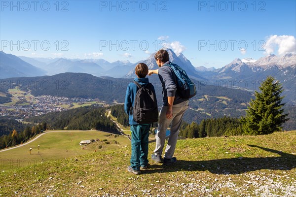 Hiking with children in Seefeld, Tyrol: Father shows his son the landscape. The snow-covered peak on the right-hand side of the picture is the Zugspitze