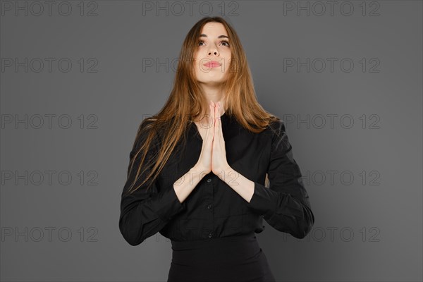 Woman holds hands in praying gesture, looking up