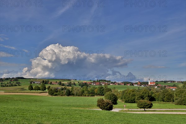Threatening thundercloud over a sunny, hilly landscape with a village in the foothills of the Alps, Kirchdorf near Haag, Upper Bavaria, Bavaria, Germany, Europe