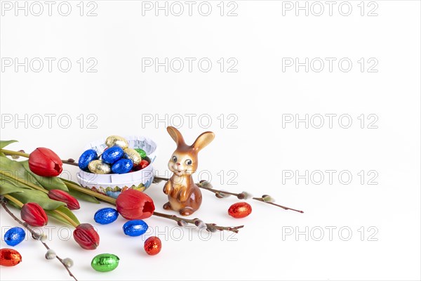 Easter composition with an Easter bunny and a bowl full of chocolate eggs, white background, copy space