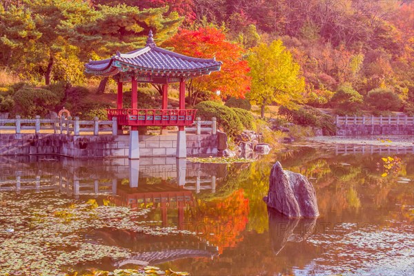 Oriental gazebo with terracotta tile roof at edge of man made pond in local public park in South Korea
