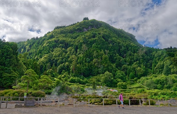 Tourists visit an area of volcanic activity surrounded by green mountains and plumes of steam, Fumarolas Lagoa das Furnas, Furnas, Sao Miguel, Azores, Portugal, Europe