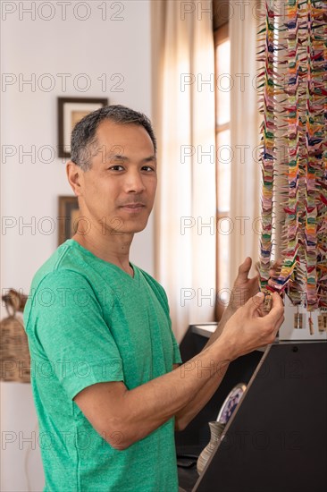 Japanese man holding a paper crane looking at camera. Memories in the family home