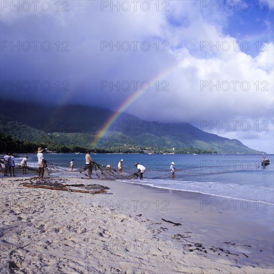 Seychelles, Mahe, Beau Vallon, fishermen pull fishing net ashore, Africa