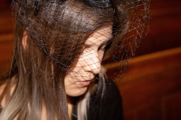 Close-up of a grieving young woman with a mourning veil in church (symbolic image)