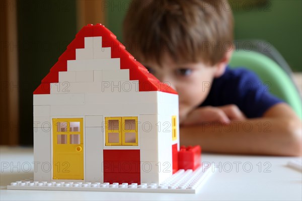 Symbolic image: Boy builds a house with building blocks