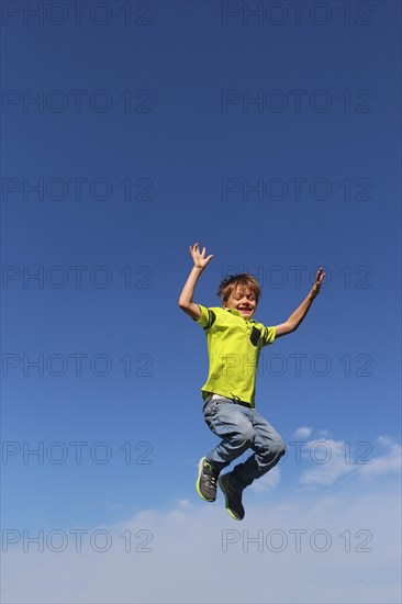 Symbolic image: Boy jumping into the air, blue sky in the background