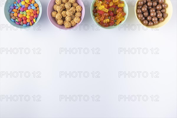 Bowls of colourful sweets on a light background, arranged at the edge of the picture