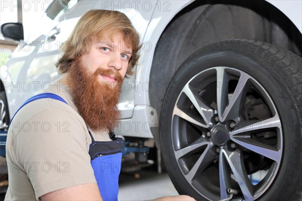 Symbolic image: Car workshop: Car mechatronics technician servicing tyres