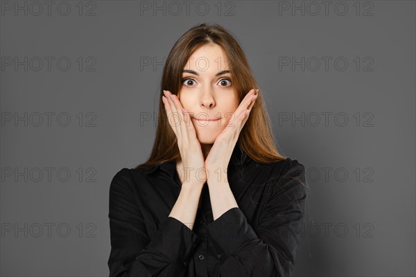 Studio portrait of surprised young woman on grey background