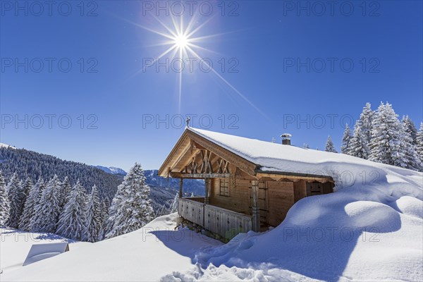 Alpine hut in winter with sun, snow, sunbeams, Hoernle-Alm, Ammergau Alps, Upper Bavaria, Bavaria, Germany, Europe