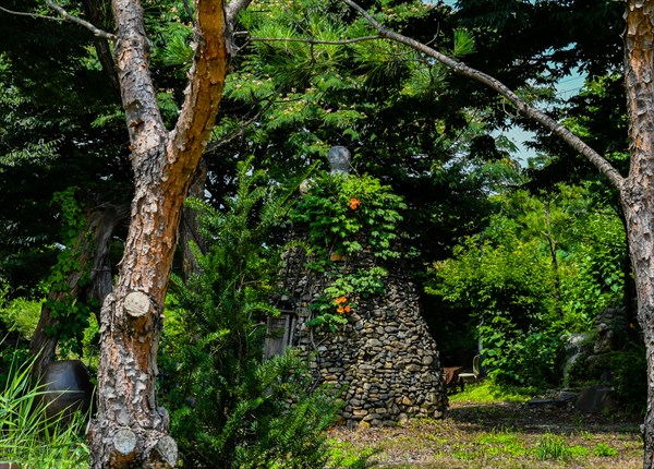 Small stone cone shaped structure with wooden door in beautiful garden in South Korea