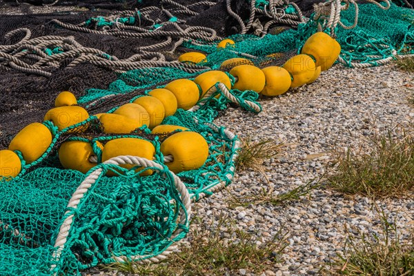 Closeup of large black and green fishing nets with yellow floats laid out on ground to dry in South Korea