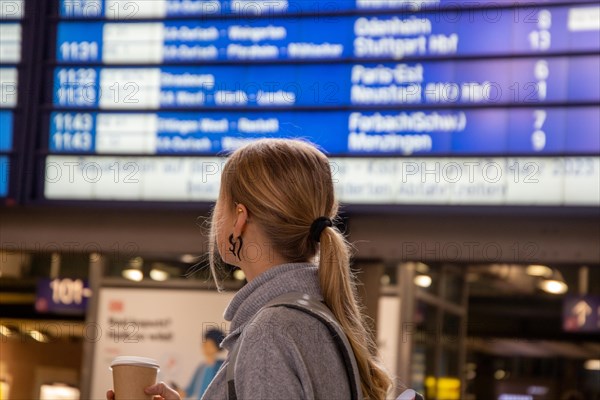 Young woman looking at the scoreboard in a railway station