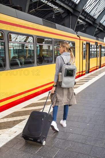 Young woman with trolley case on the railway track