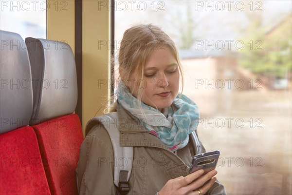Young woman on the train looks at her smartphone