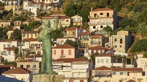 Statue raises its arm over a Mediterranean settlement with densely packed houses, Gythio, Mani, Peloponnese, Greece, Europe