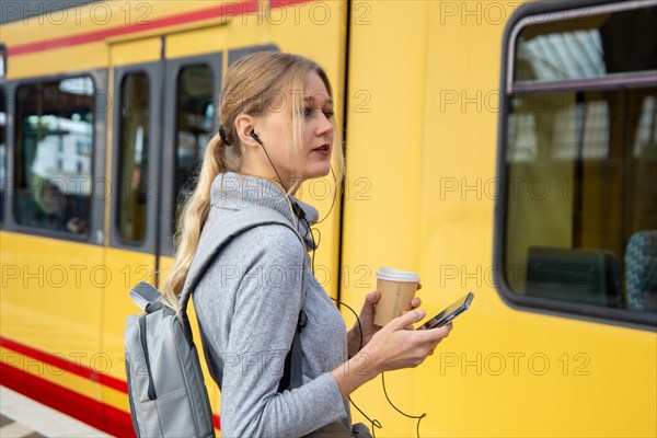 Close-up of a young woman in front of a train at the station