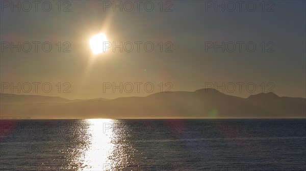 The rising sun over the sea near the horizon in a peaceful atmosphere, Gythio, Mani, Peloponnese, Greece, Europe