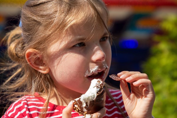 Seven-year-old girl eats a chocolate kiss at a folk festival