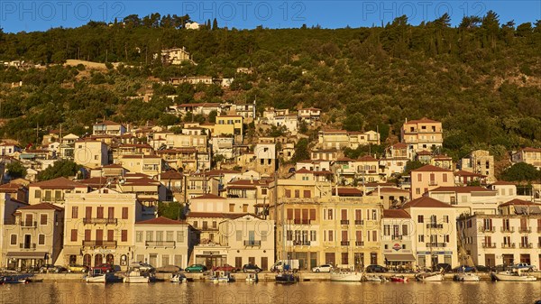 The morning light illuminates the lively coastal panorama and the busy harbour, Gythio, Mani, Peloponnese, Greece, Europe