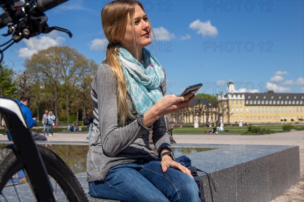 Young woman with bicycle enjoying the spring weather in Karlsruhe Palace Gardens (symbolic image)