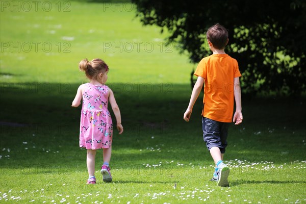 Boy and girl (siblings) running in a meadow